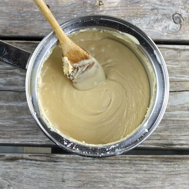 Penuche frosting in a saucepan with wooden spoon.