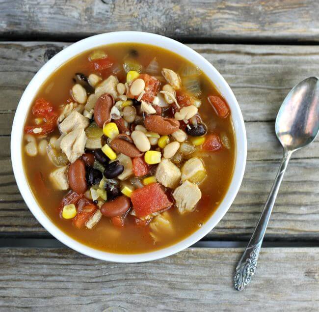 Looking down at a bowl of bean soup with a spoon by the side of the bowl.