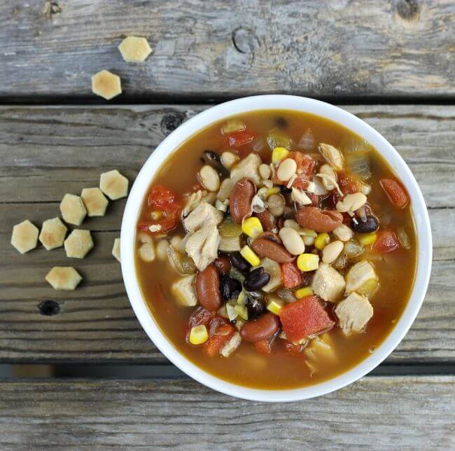 Looking down at a bowl of soup with oyster crackers on the side.