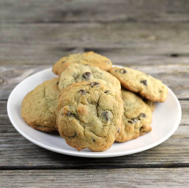 Stack of chocolate chip cookies on a white plate.