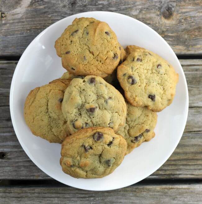 Chocolate chip cookies piled on a white plate.