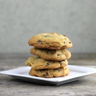Stacked chocolate chip cookies on a white plate.