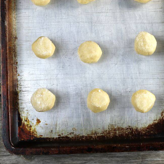 Unbaked cookie balls on a baking sheet.