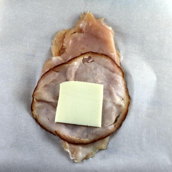 Chicken breast with a slice of ham and cheese on top.