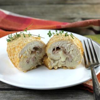 Chicken cordon bleu on a white plate place on a orange napkin.