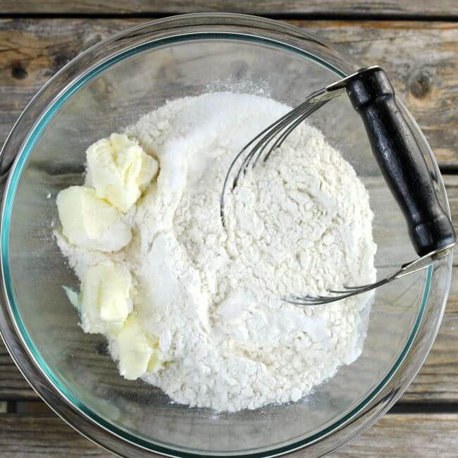 The butter is added to the dry ingredients with a pastry cutter in the bowl.