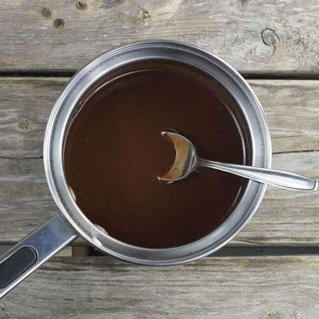 Melted chocolate in a saucepan with a spoon sticking out of the pan.