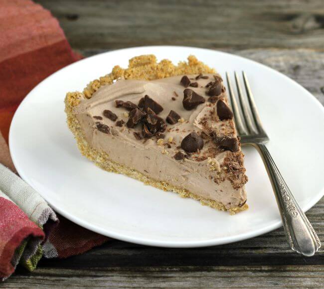 Chocolate pie on a white plate with a fork and napkin under the plate.