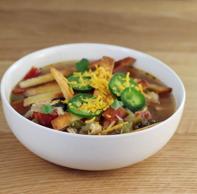 A side view of a bowl of Mexican tortilla chicken soup.