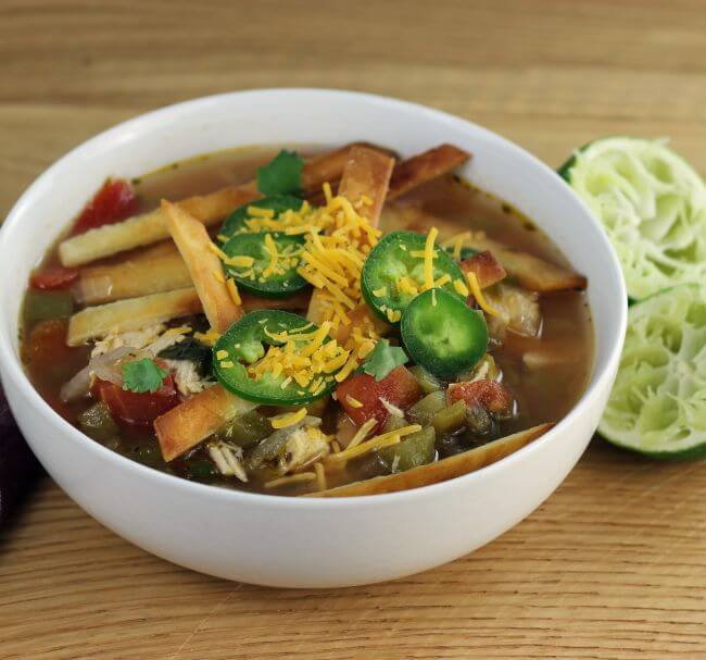 Side angle view of a bowl of chicken tortilla soup.