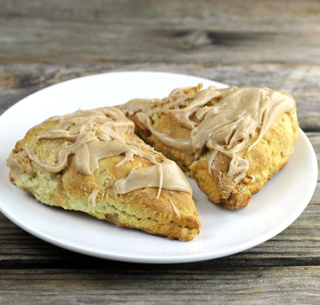 Side view of two apple scones on a white plate.