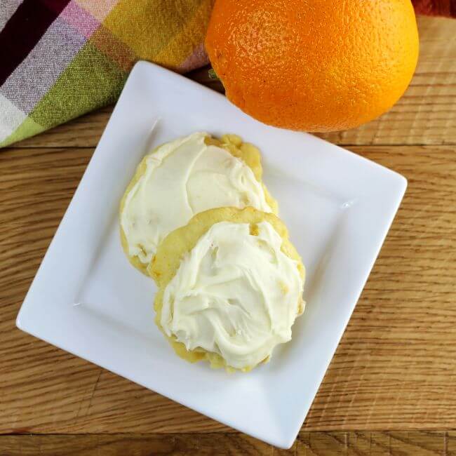 Looking down at a plate of cookies with an orange on the side.