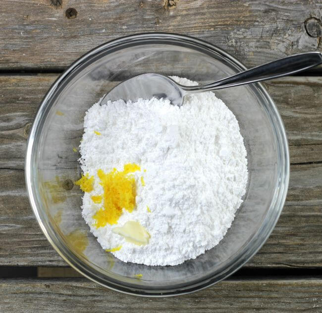 Powdered sugar, lemon zest. and butter in a glass bowl.