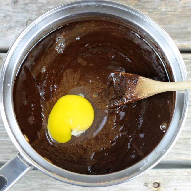 Choclate mixuter with egg and spoon in a saucepan.