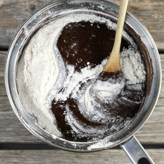 chocolate mixture with flour in saucepan and wooden spoon.