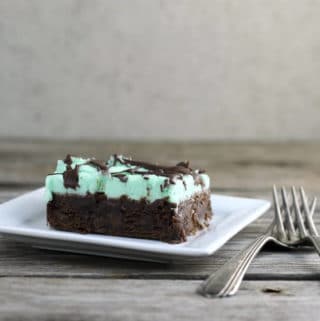 Brownie with green mint frosting on a white plate with forks