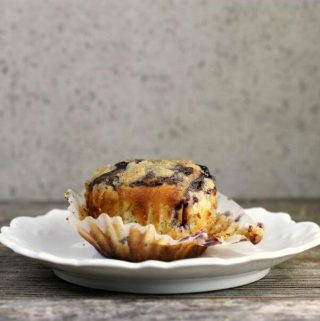 unwrapped blueberry muffin on a white plate