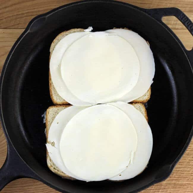 Cheese is placed on top of the bread in the skillet.
