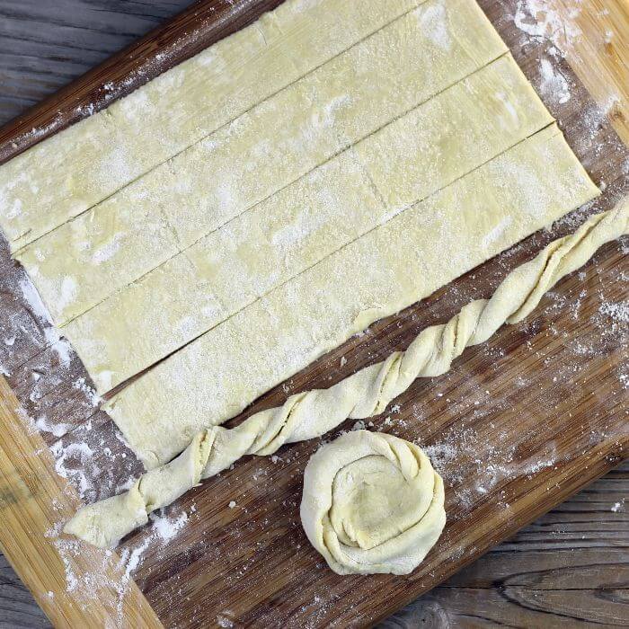 Cutting the pastry into strip, then twisting them, and then making a coil.