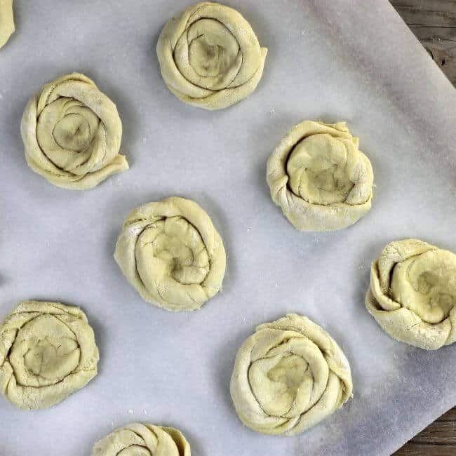 Puff pastry coils are placed on the baking sheet that is lined with parchment paper. 