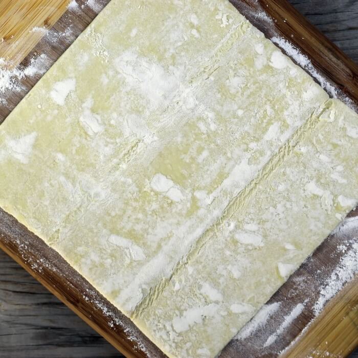Puff pastry sheet is placed on the flour surface.