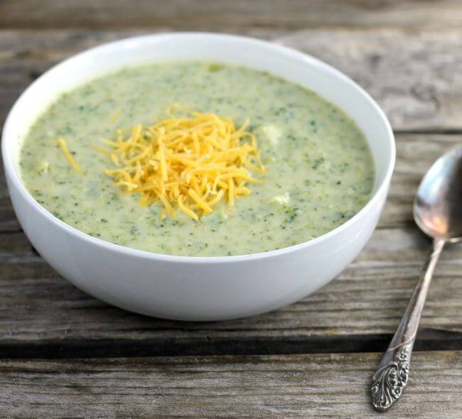 Side angle view of cheese broccoli soup in a white bowl.