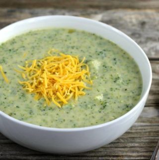 Side view of broccoli soup with cheese on top of the soup.