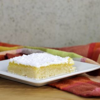 Side view of a lemon bar on a white plate.