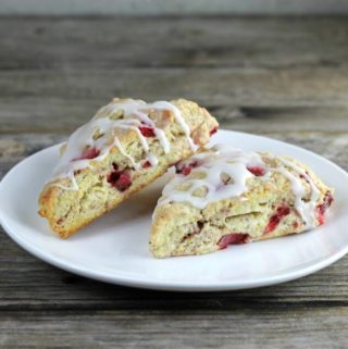Side angle view of two lemon strawberry scones on a white plate.