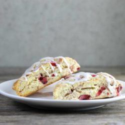 Side view of two strawberry scones on a white plate.