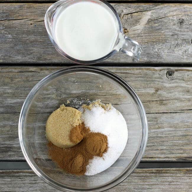 Sugar, and cinnamon in a bowl next to a measuring cup of milk.
