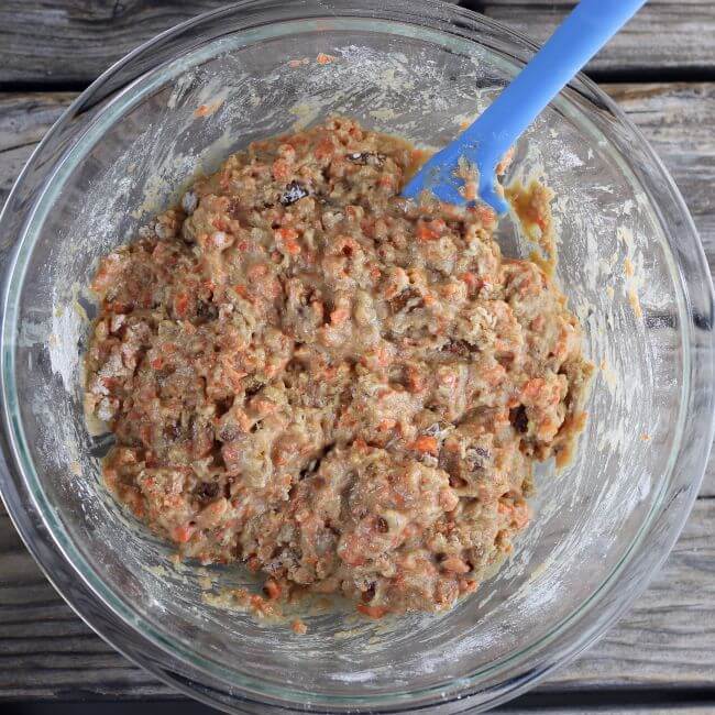 Carrot muffin batter in a bowl with a blue spatula.