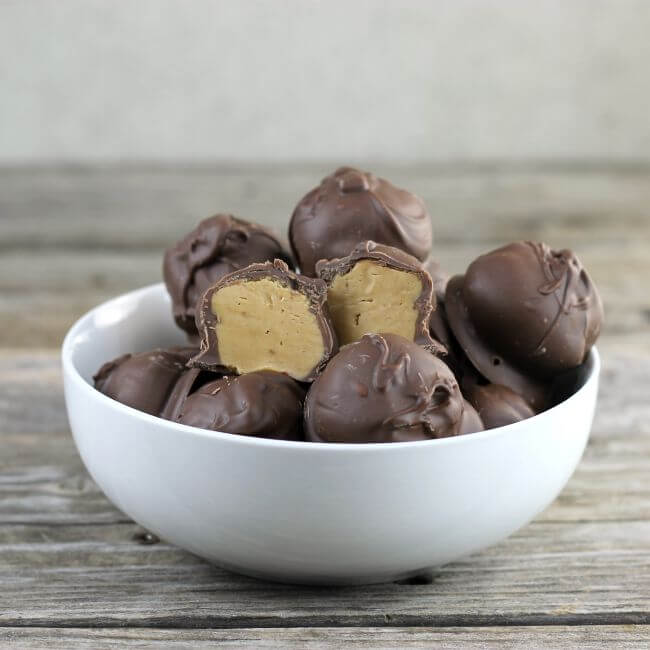 Peanut butter balls with one cut in half in a white bowl.