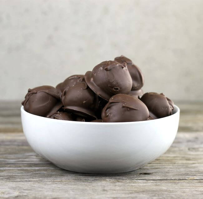 Bowl of peanut butter balls sitting on a wooden table.