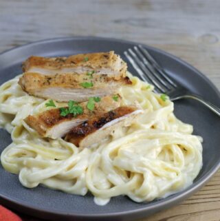 A side angle view of a plate of chicken alfredo.