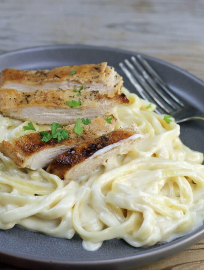 A side angle view of a plate of chicken alfredo.