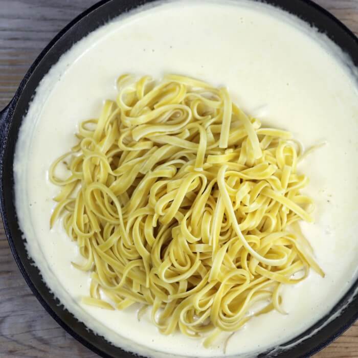 Fettuccini pasta is added to the skillet with the cream sauce.