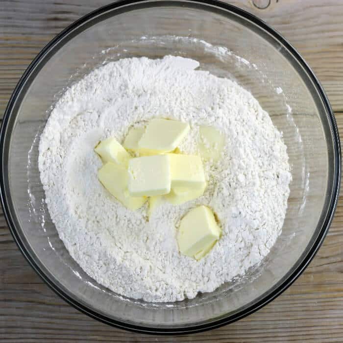 Butter pieces are added to the bowl with the flour mixture. 