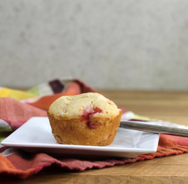 A side view of a muffin on a white plate with a plaid napkin.