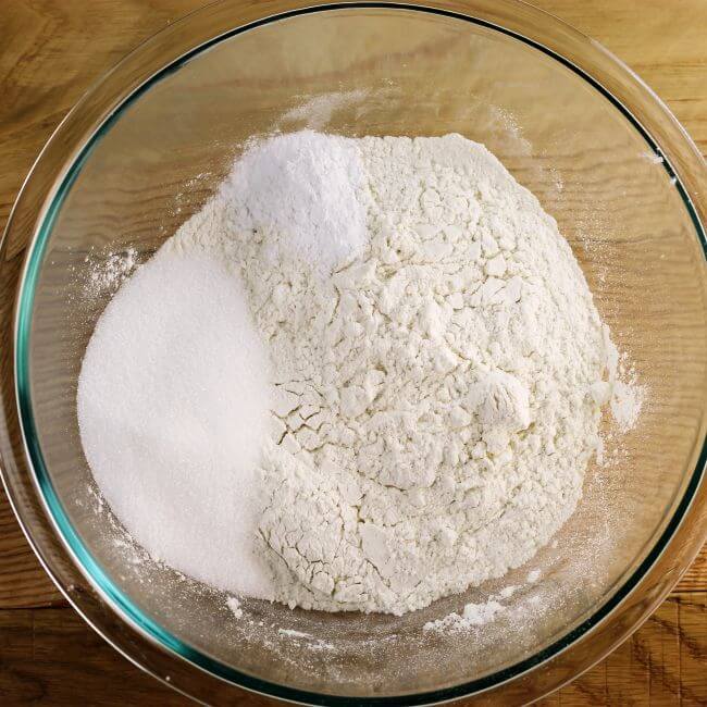 Flour, sugar, baking powder, baking soda, and salt in a glass bowl.
