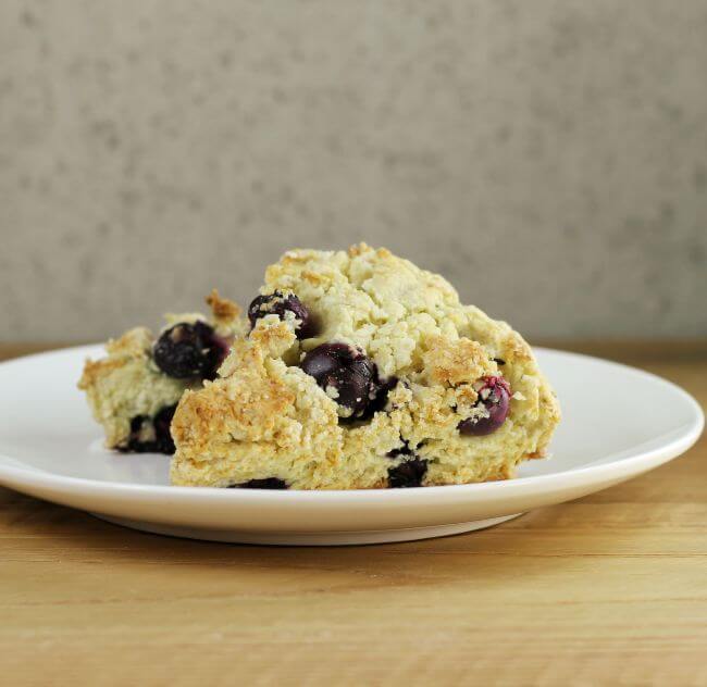 Side angle view of two scones on a white plate.