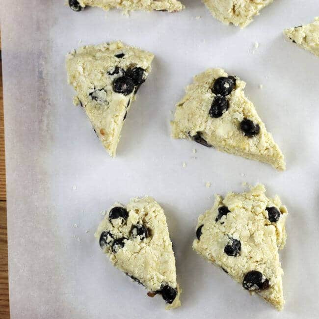 Unbaked blueberry scones on a baking sheet.