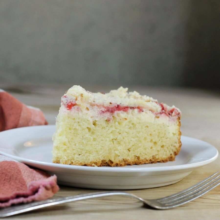 A side view of a strawberry coffee cake with a fork in front of the plate.