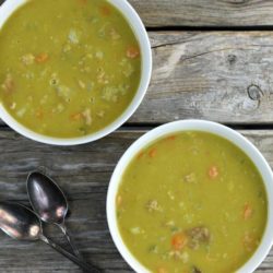 Two bowls of split pea soup with two spoons on the side.