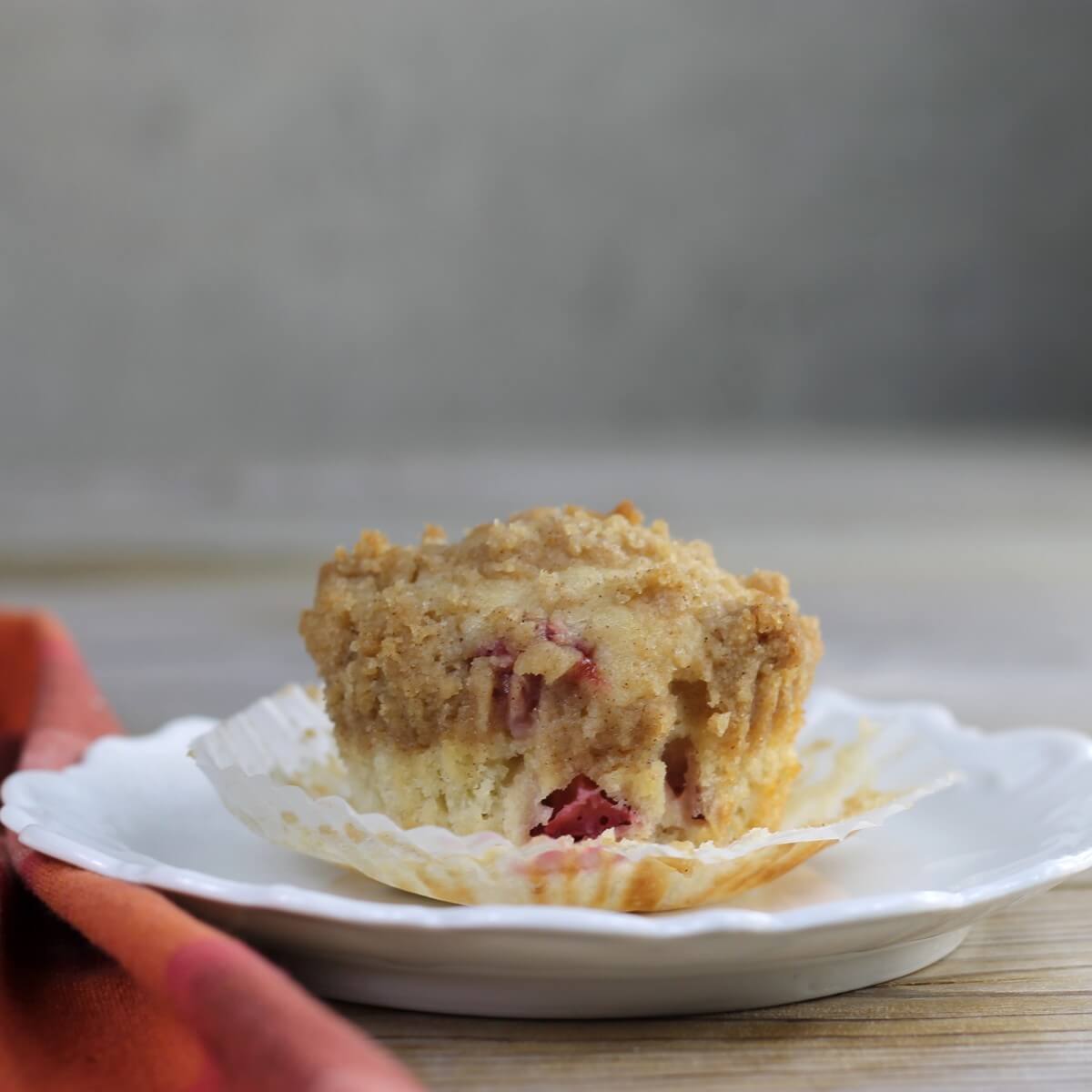 A strawberry rhubarb muffin on a white plate. 