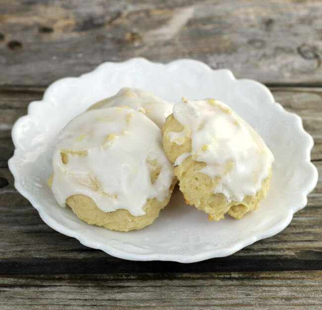 Frosted lemon cookies on a white plate.