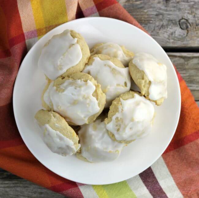 Frosted cookies piled on a white plate with a napkin under the plate.