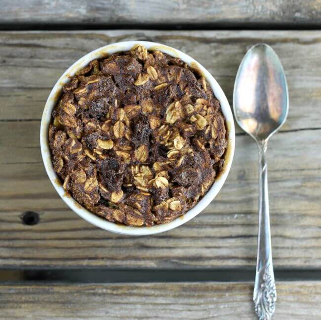 Looking down at a baked oatmeal in a ramekin with a spoon on the side.