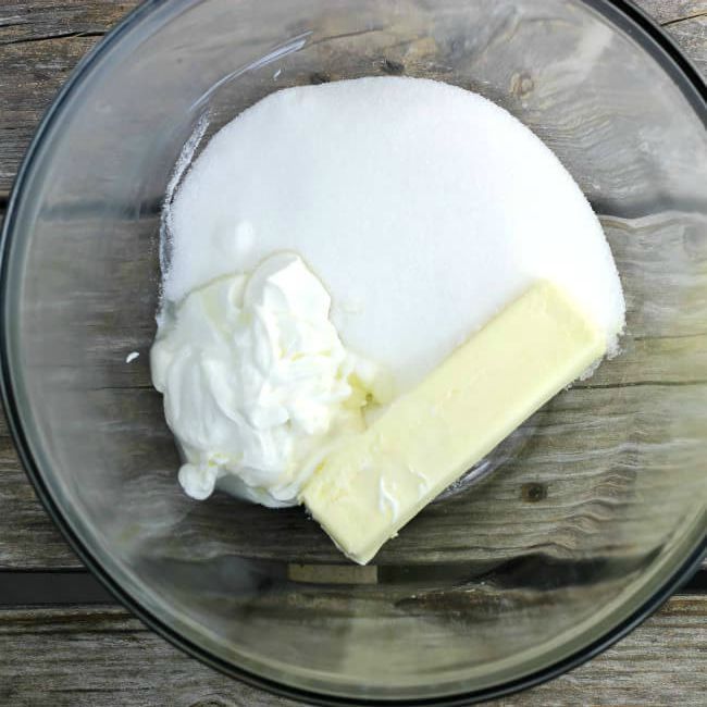 Butter, sugar, and sour cream in a glass bowl.