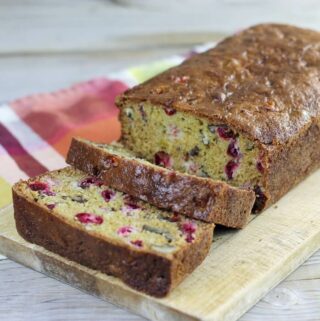 A loaf of cranberry nut bread with a couple of slices cut.